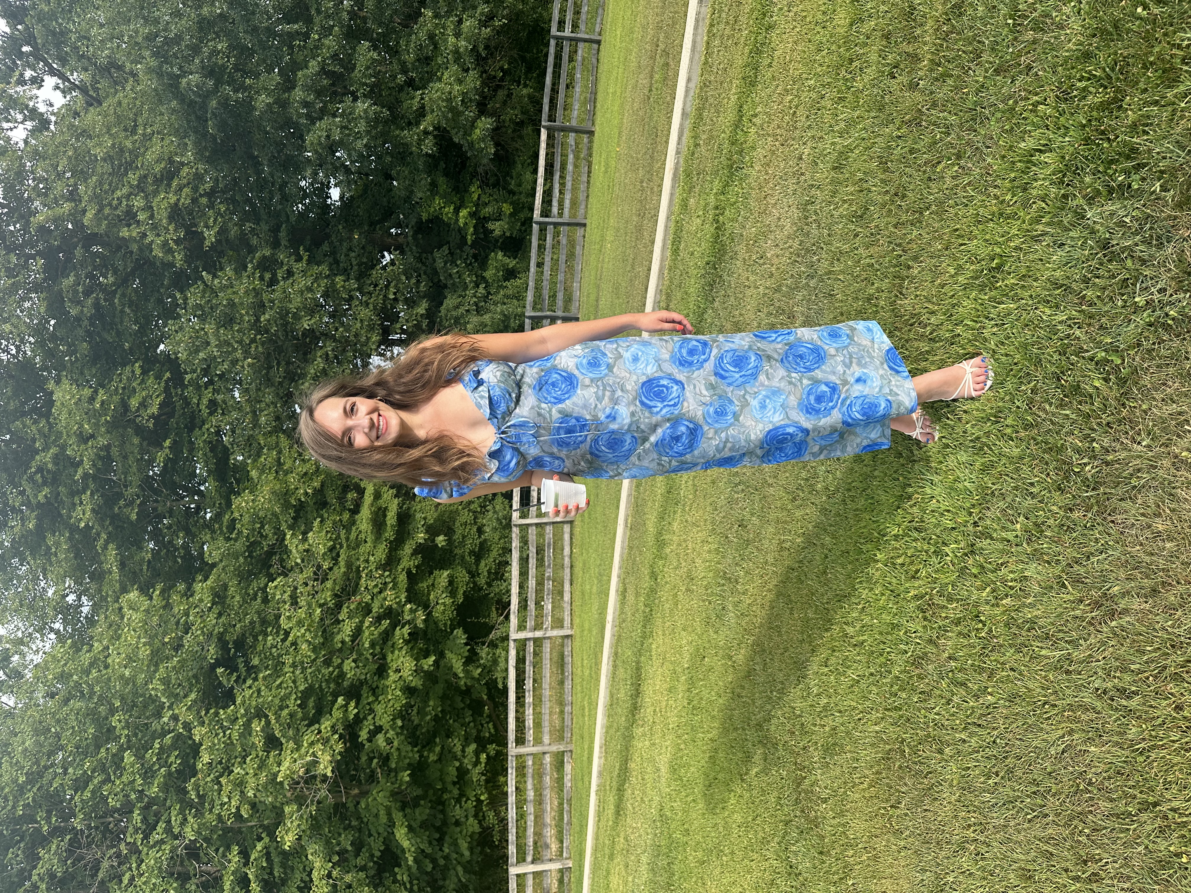 Emily standing outside on the grass wearing the finished Nelly Dress in grey-blue rose print silk